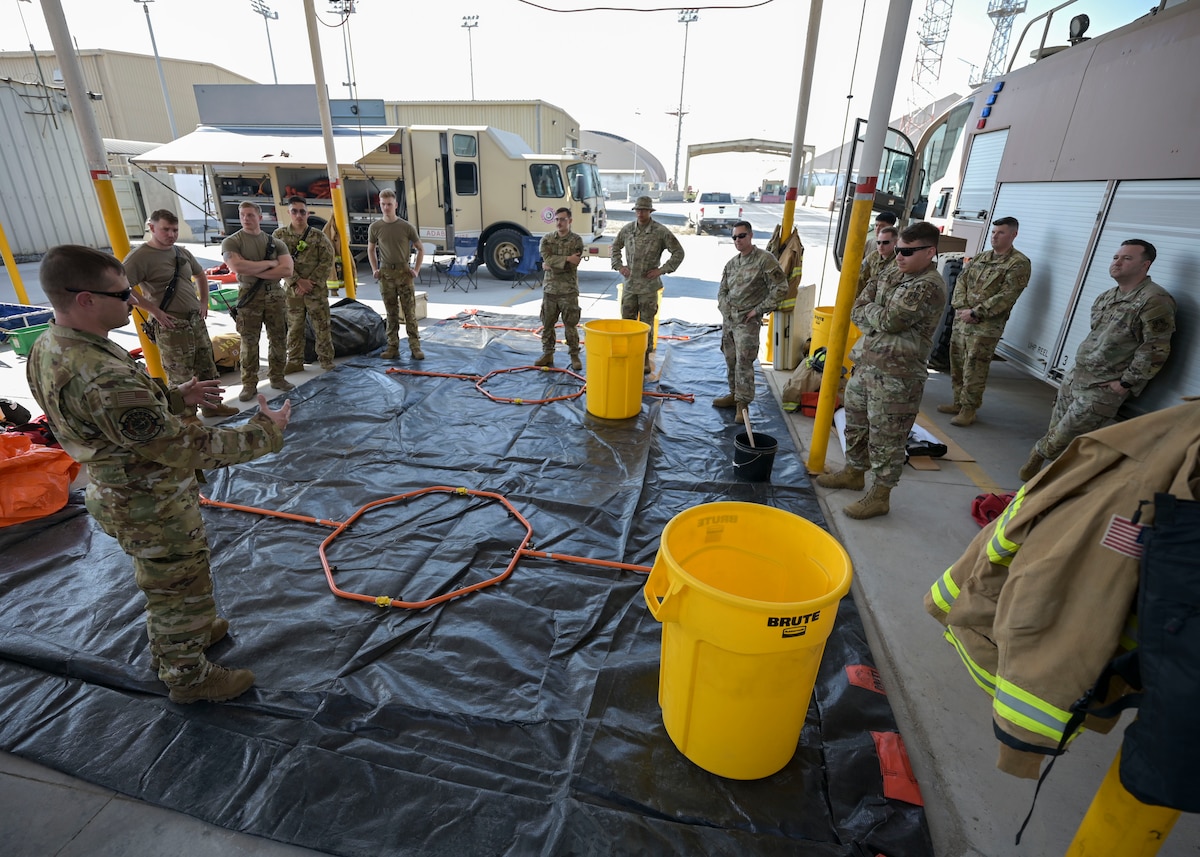 People in military unifroms gather on a large tarp and look at metal hoops.