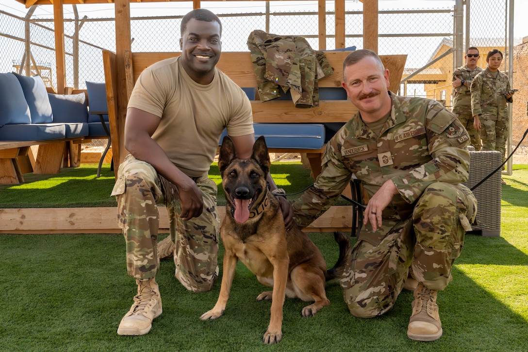 U.S. Air Force Chief Master Sgt. Joshua VanDerbeck, 332nd Air Expeditionary Wing command chief, right, and Chief Master Sgt. Nicholas Jackson, 332nd Expeditionary Air Base Group senior enlisted leader, pose with military working dog Fany, center,  in the U.S. Central Command area of responsibility, Nov. 13, 2025. The EABG leadership toured the 332nd Expeditionary Security Forces Squadron K9 facilities and capped it off with a volunteer-only demonstration in a bite suit. (U.S. Air Force photo by Senior Airman Kari Degraffenreed)