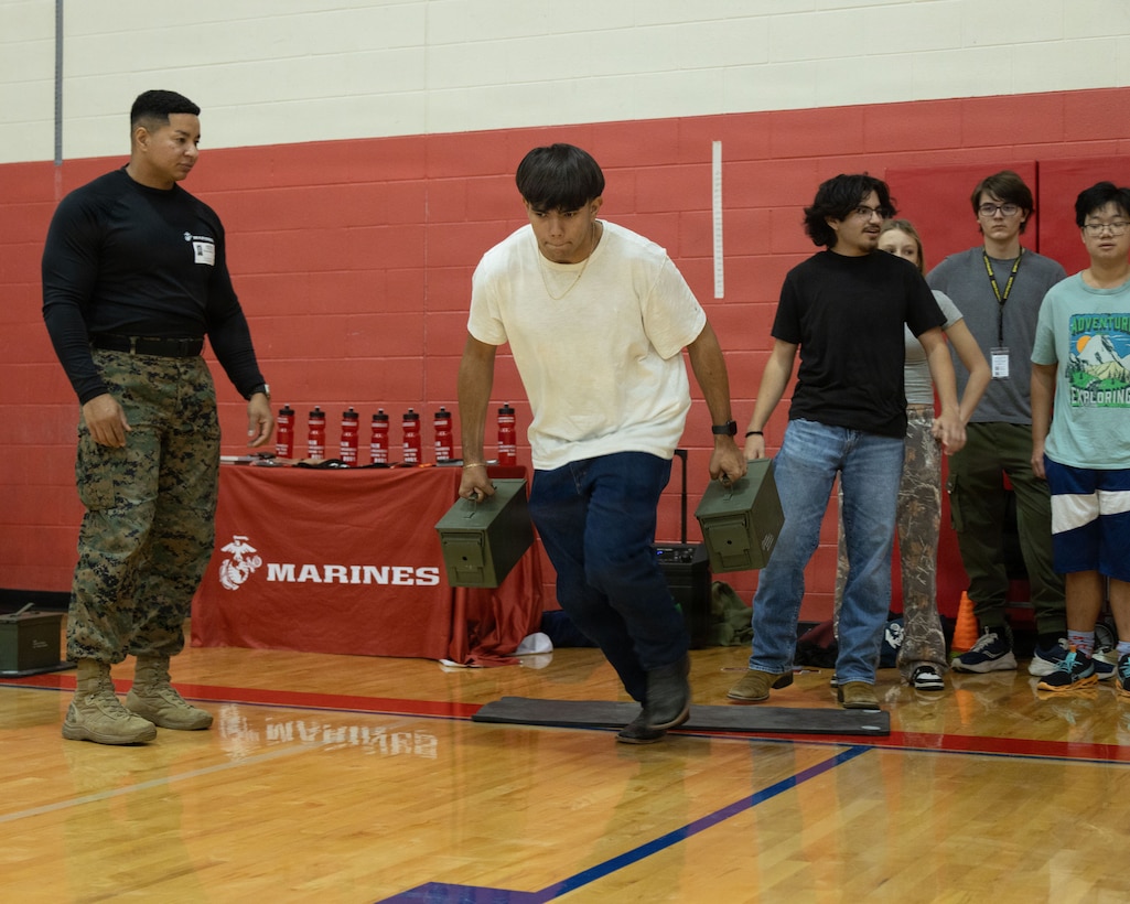 A student with Jack C. Hays High School participates in an ammo can relay race during a weight room takeover with Glazier Clinics at Jack C. Hays High School in Buda, Texas, Dec. 4, 2025. Glazier Clinics hosted a weight room takeover which helps recruiters connect with students, showcase Marine Corps values and career paths available, and create memorable, high-energy experiences. (U.S. Marine Corps photo by Sgt. Jose D. Cruz)