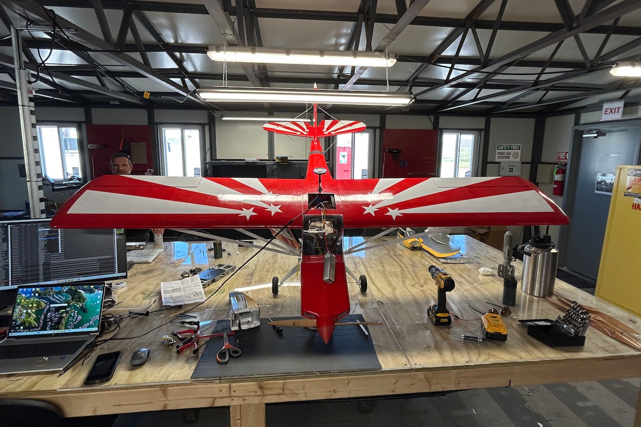 A large drone that looks like a small airplane sits atop a wooden table.