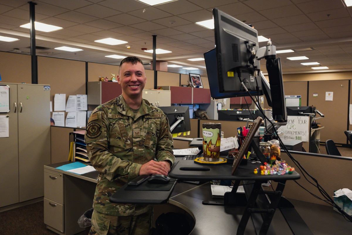 Senior Airman Damien Stevens poses for a photo at his desk.