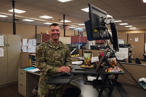 Senior Airman Damien Stevens poses for a photo at his desk.