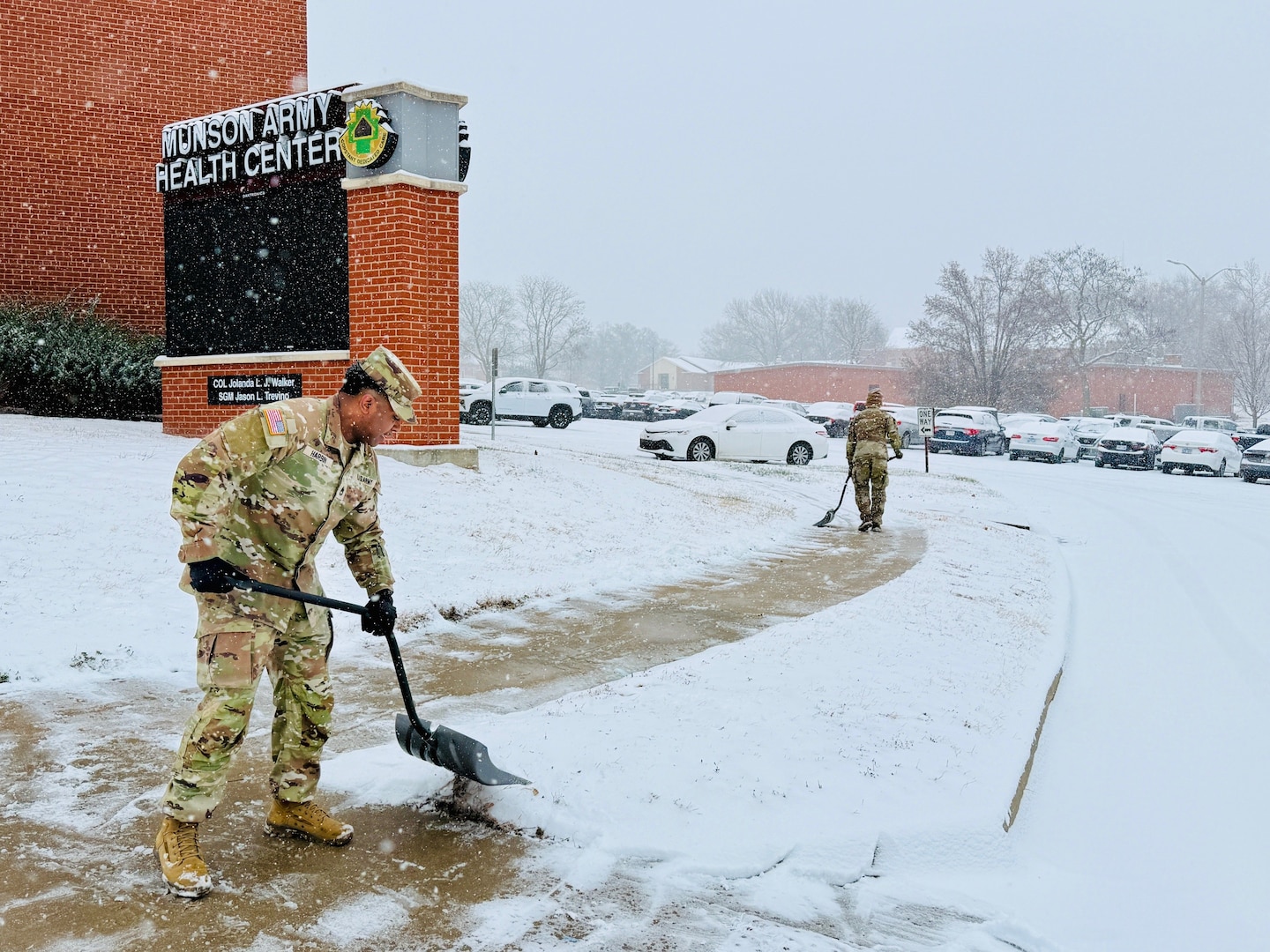 Sgt. 1st Class Marcus Harbin, Munson Army Health Center operations NCOIC, helps clear snow and ice from a sidewalk outside the facility during a winter storm, Monday, Dec. 1. Snow removal teams tended to sidewalks and parking areas for patient and staff safety as more than four inches fell on Fort Leavenworth during the day.