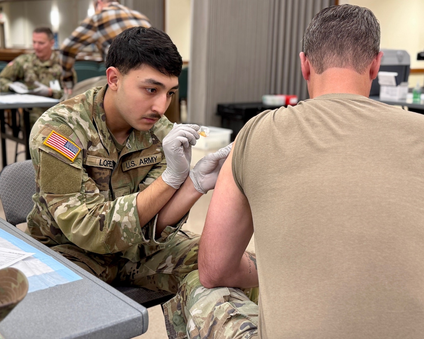 Munson Army Health Center Combat Medic Specialist Pfc. Antonio Lopez administers a seasonal influenza vaccine to a service member at a walk-in community flu-shot event at Frontier Chapel, Fort Leavenworth, Kansas, Nov. 19. According to Munson public health officials keeping flu from formations on post, including the U.S. Army Command and General Staff College and the historic United States Disciplinary Barracks, the only maximum-security prison in the Department of War, is an important Force Health Protection mission.