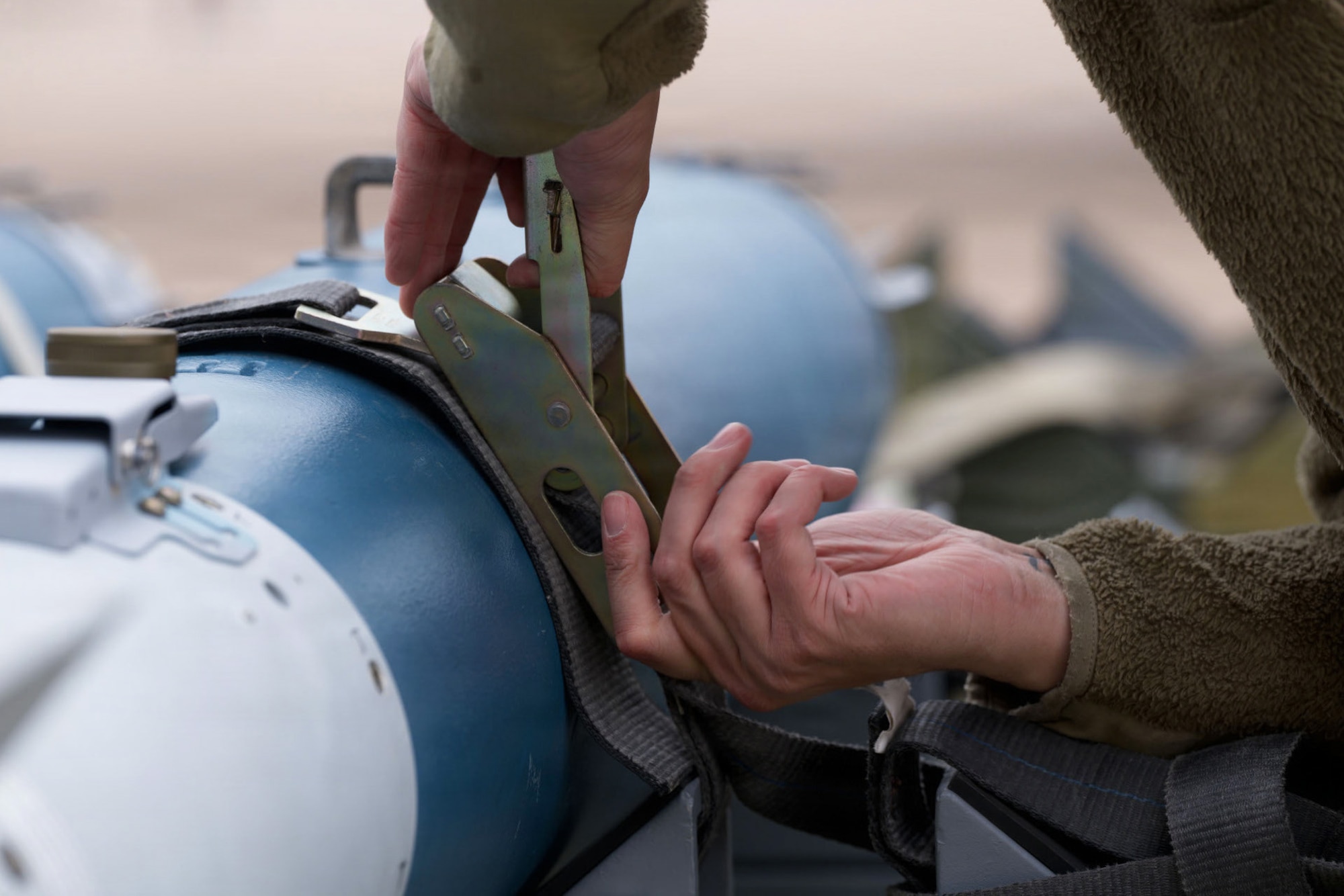 U.S. Air Force Staff Sgt. Jordan Arthur, 28th Bomber Generation Squadron weapons load crew chief, secures a guided bomb unit during the annual Weapons Load Crew of the Year competition at Dyess Air Force Base, Texas, Dec. 4, 2025. Teams were tested on a variety of technical aspects of munitions loading while under time constraints. (U.S. Air Force photo by Senior Airman Emma Anderson)