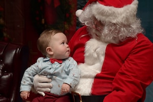 Santa holds a little boy on his lap.