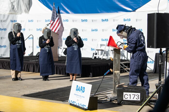 NNS welder Andrew Kahler weld the initials of Bove onto a metal plate during the keel authentication ceremony for Virginia-class attack submarine Barb (SSN 804) on Tuesday, Dec. 9, 2025 at HII’s Newport News Shipbuilding division. The metal plate will remain affixed to the submarine throughout its life