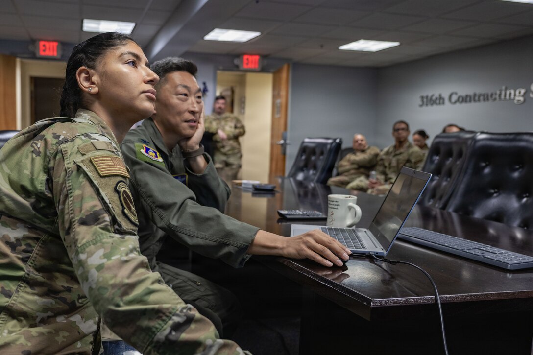 U.S. Air Force Staff Sgt. Janet Benitez, contracting officer assigned to the 316th Contracting Squadron, shows U.S. Air Force Col. Jun S. Oh, 316th Wing and installation commander, how to complete a contract modification.