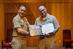 ENS Brett Wiggington, formerly Chief Electronics Technician (Nuclear), receives an award from U.S. Navy Capt. Michael Eberlein during a commissioning ceremony.