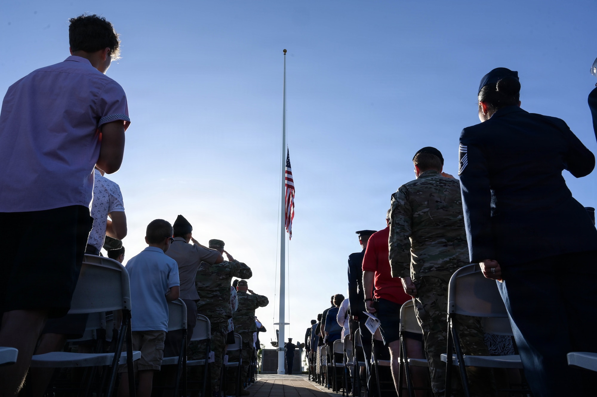 Attendees render a salute and display respects during the raising of the U.S. flag