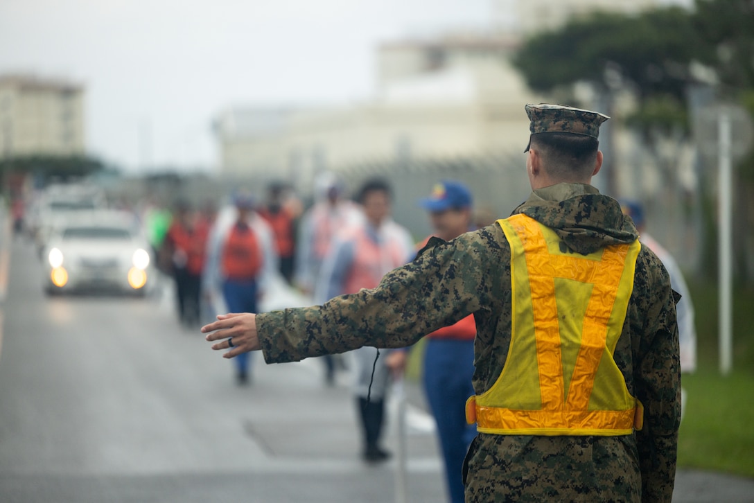 U.S. Marine Corps Cpl. Noah Uhrbrock, a calibration technician assigned to Intermediate Repair Company, 3rd Maintenance Battalion, 3rd Marine Logistics Group, directs local Japanese volunteers from Uruma City during a tsunami evacuation exercise at Camp Kinser, Okinawa, Japan, Nov. 18, 2025. Uhrbrock, a Texas native, and other Marines guided local Japanese volunteers through an evacuation route on Camp Kinser. (U.S. Marine Corps photo by Cpl. Thomas Sheng)