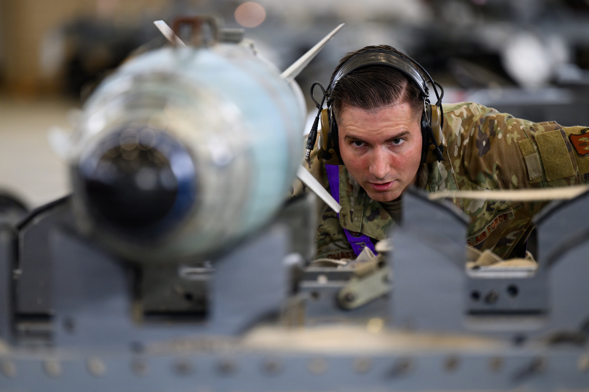 A person looks at a bomb as it is about to be loaded onto aircraft.