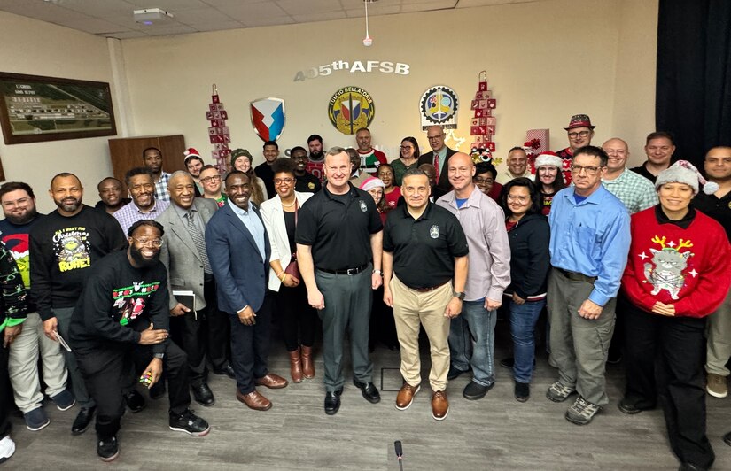 Army Maj. Gen. Eric Shirley, U.S. Army Sustainment Command’s commanding general, and Command Sgt. Maj. Jason Gusman, ASC’s senior enlisted leader, (center) pose for a group photo with the 405th Army Field Support Brigade team at their holiday celebration event at the brigade headquarters in Kaiserslautern, Germany, Dec. 9.