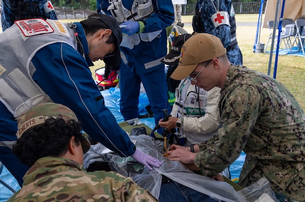 JOGASHIMA PARK, Japan (Nov. 9, 2025) — A U.S. Navy Hospital Corpsman assigned to U.S. Navy Medicine Readiness and Training Command Yokosuka works with Japanese responders to assess and treat a simulated casualty during Big Rescue Kanagawa 2025. The annual exercise is one of Kanagawa Prefecture’s largest disaster-response drills, involving U.S. Naval Hospital Yokosuka, Red Cross Yokosuka and Branch Health Clinic Atsugi personnel working alongside U.S. and Japanese agencies.(U.S. Navy photo by Daniel Taylor/USNMRTC Public Affairs)
