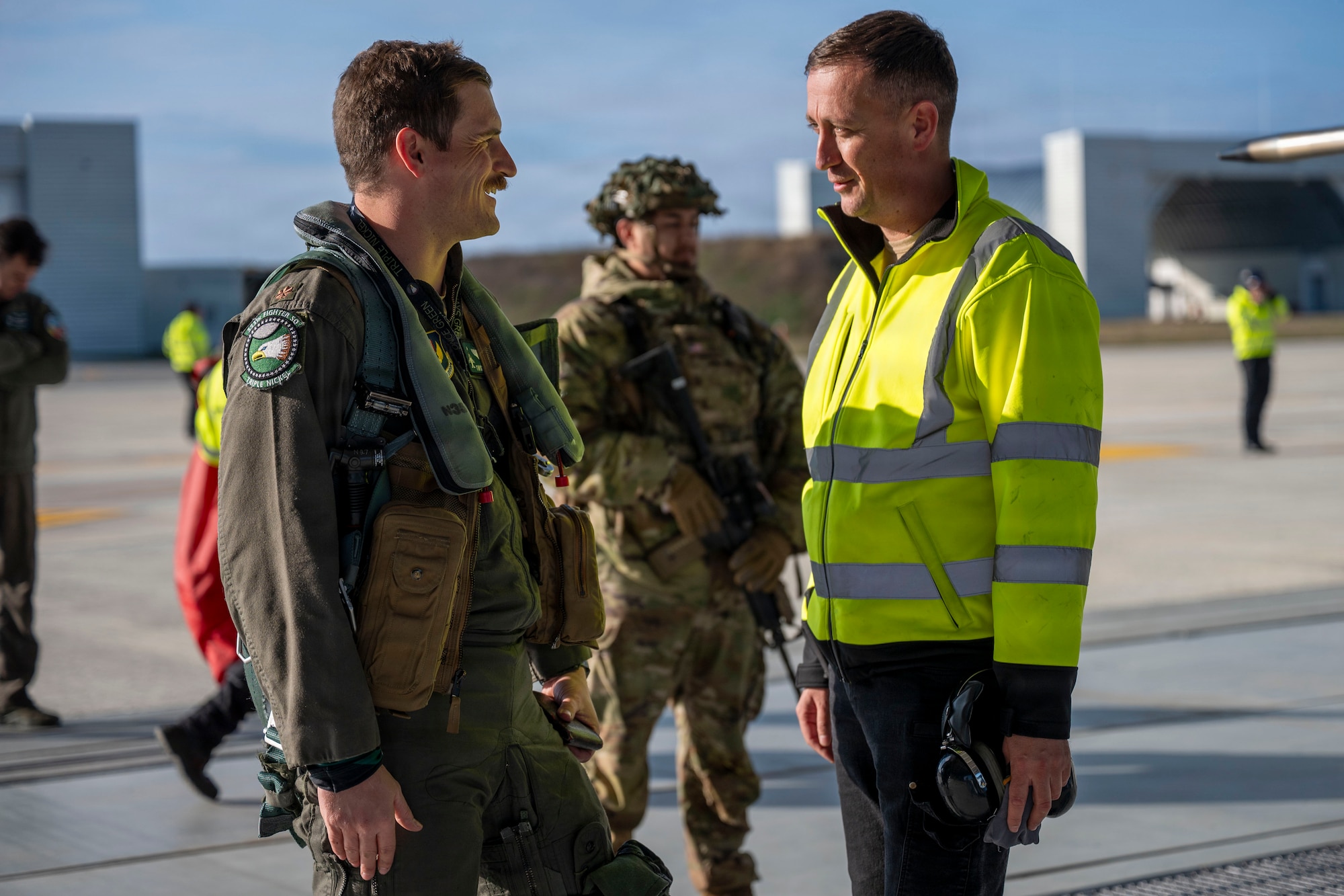 U.S. Air Force Maj. John McGee, 555th Fighter Squadron F-16 Fighting Falcon pilot, speaks with a Romanian Air Force member during an Agile Combat Employment training mission to Campia Turzii, Romania
