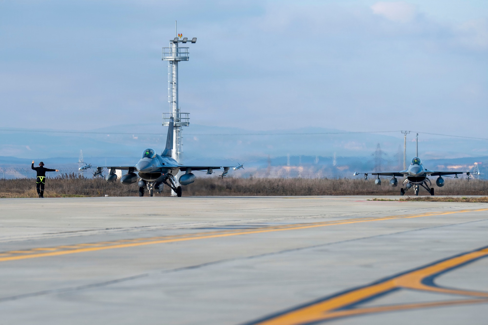 Two U.S. Air Force F-16 Fighting Falcons, assigned to the 510th and 555th Fighter Generation Squadrons at Aviano Air Base, Italy, taxi down the runway during routine Agile Combat Employment operations at Campia Turzii, Romania
