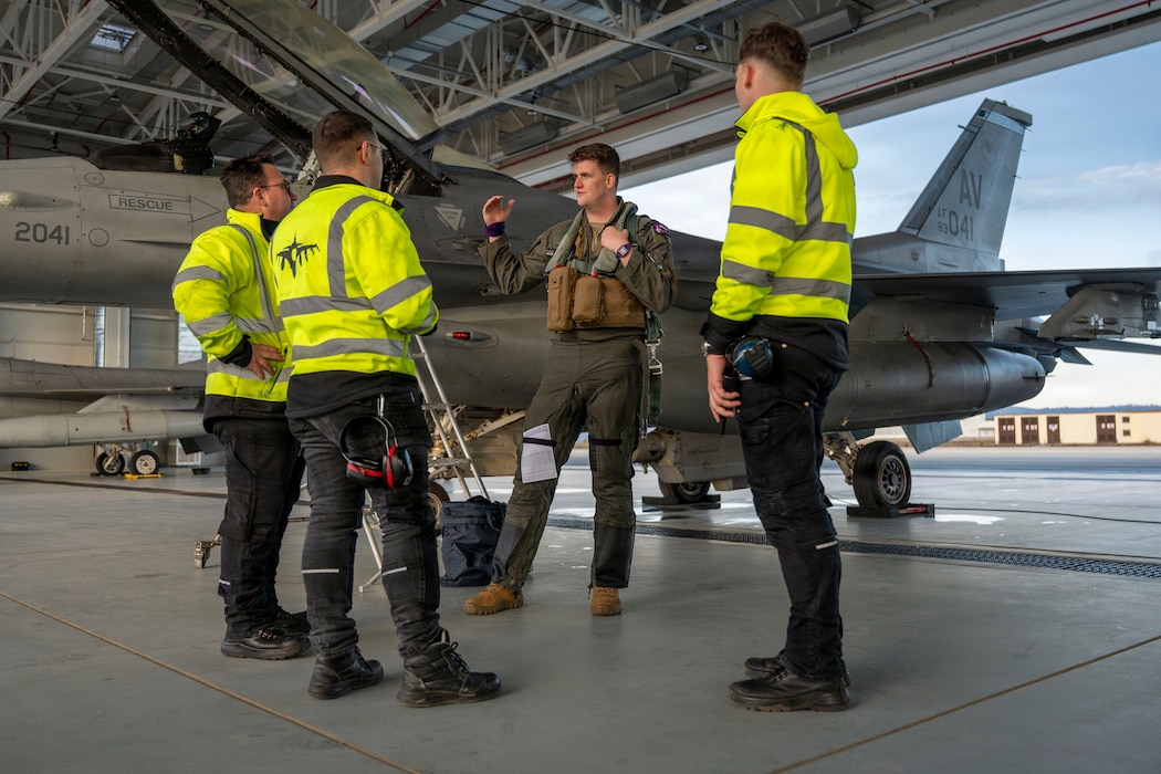 U.S. Air Force Capt. Kenneth Roberts, 510th Fighter Squadron F-16 Fighting Falcon pilot, speaks with Romanian Air Force members after a refueling at Campia Turzii, Romania