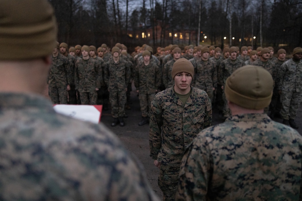 U.S. Marine Corps Cpl. Jordan Morrison, center, a combat engineer, and 1st Lt. Cameron Quinn, right, an engineer officer, both with Combat Logistics Battalion 6, Combat Logistics Regiment 2, 2nd Marine Logistics Group, stand at attention, while Gunnery Sgt. David Freeman, an engineer operations chief, with CLB 6, CLR 2, 2nd MLG, reads a promotion warrant,  during Exercise Freezing Winds 2025 in Dragsvik, Finland, Dec. 5, 2025. Freezing Winds is conducted to increase interoperability between Marines, Finland, and NATO Allies by executing combined amphibious operations in and around the Baltic Sea littorals, and is part of a regularly occurring series of exercises in northern Europe that demonstrates the capability to deploy and train Marines and Sailors in support of the NATO Alliance. Morrison is a native of Texas. Quinn is a native of Vermont. Freeman is a native of Maryland. (U.S. Marine Corps photo by Cpl. Apollo Wilson)