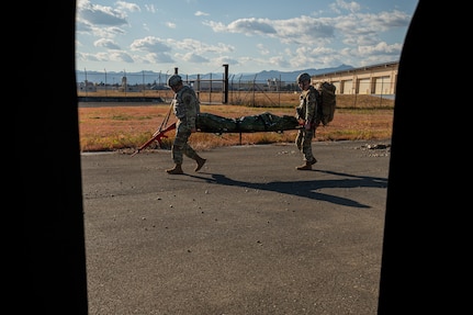 Two Airmen carry a stretcher.