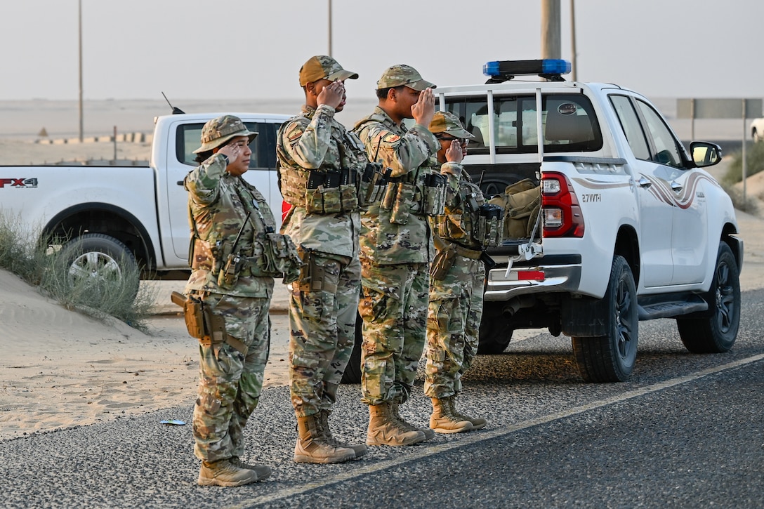 Defenders for the 386th Expeditionary Security Forces Squadron salute a passing motorcade during a USO Holiday Tour within the U.S. Central Command area of responsibility, Dec. 4, 2025. The visit underscored America’s globally integrated and forward-ready Joint Force, highlighting the enduring commitment of U.S. Service Members and the USO’s mission to connect and sustain the force wherever they serve. (U.S. Air Force photo by Tech Sgt. Andrew Schumann)