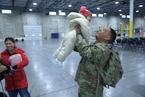 U.S. Army Pfc. Adrian Hernandez of the Illinois Army National Guard’s 2nd Battalion, 130th Infantry Regiment, holds his 1-year-old daughter, Catalina, as he reunites with his family at a homecoming ceremony Dec. 6, 2025.