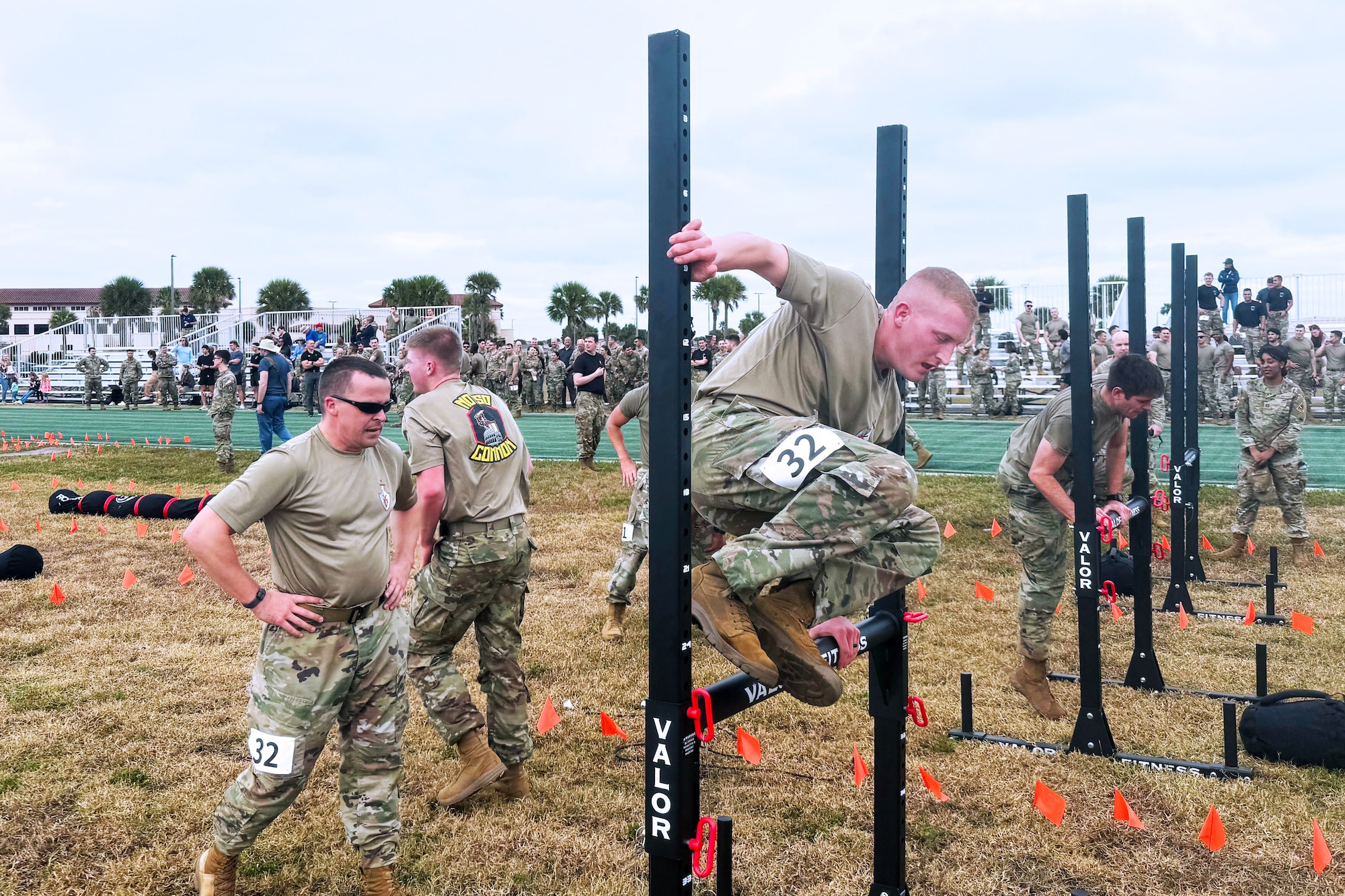 One military member vaults over a low beam while others wait in line to do the same