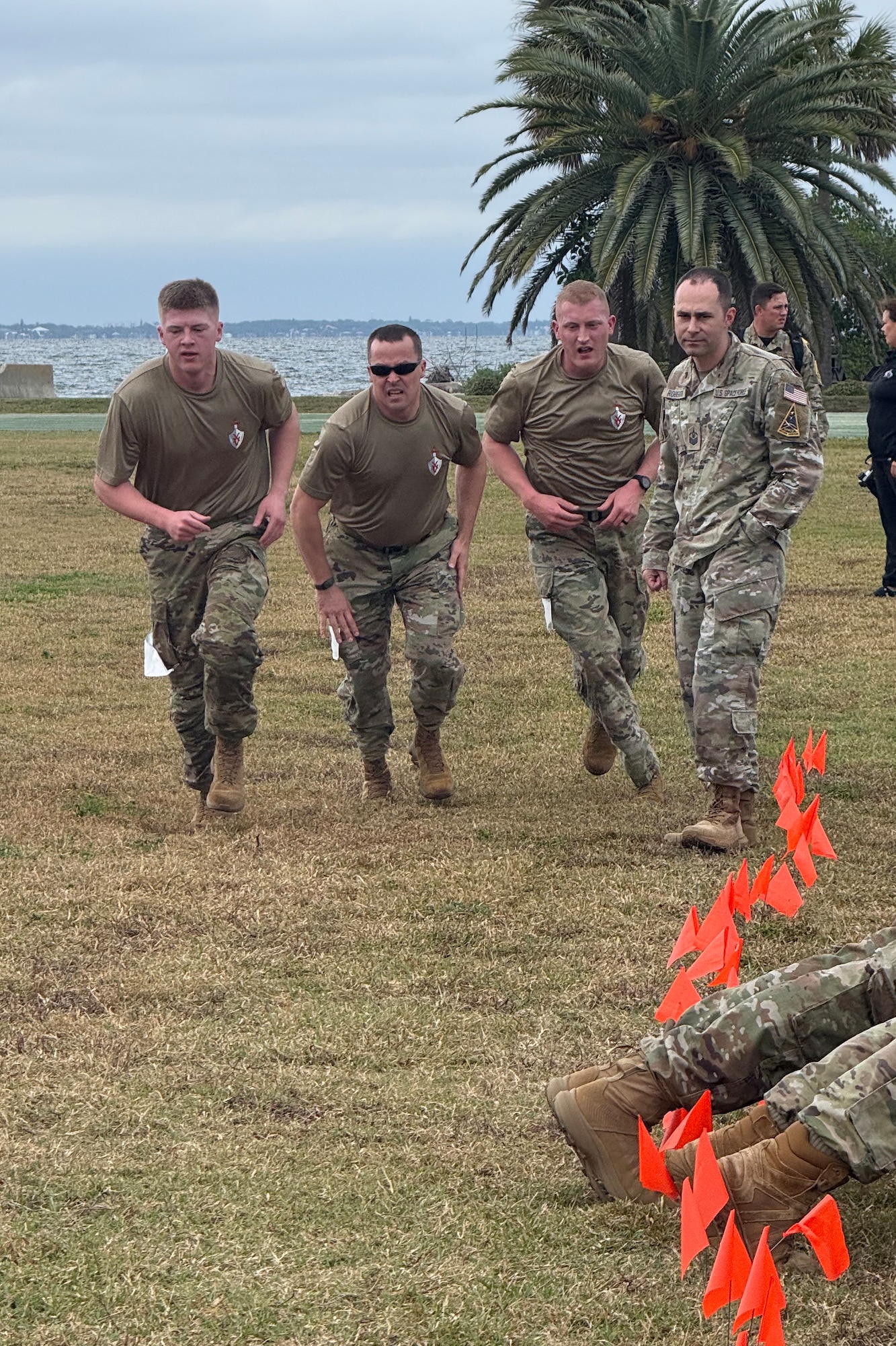 Three men in military uniforms run through a field