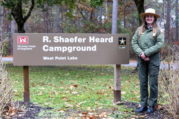 Female Park Ranger standing by a sign.