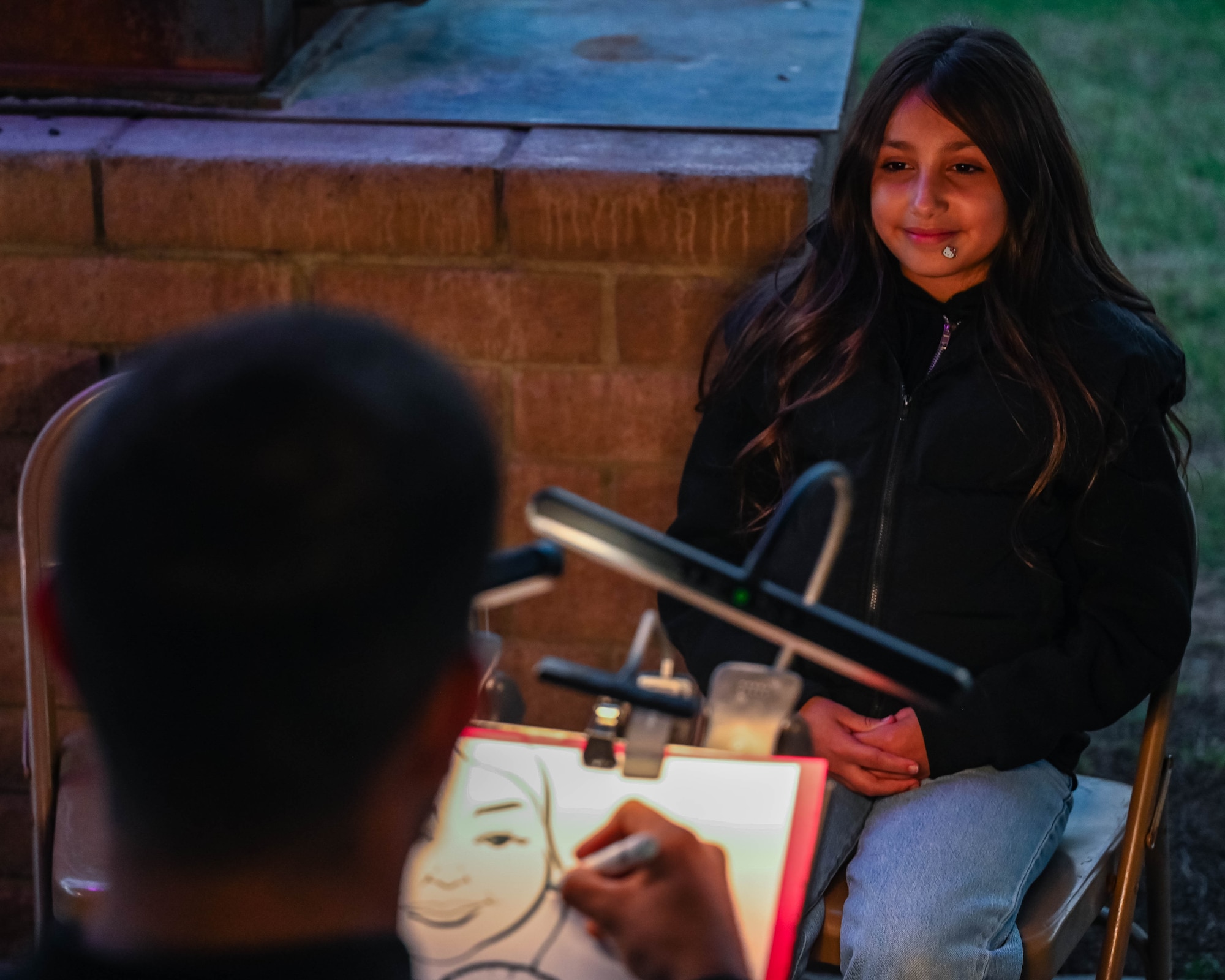 An artist paints a military child's portrait, Dec. 5, 2025, at Luke Air Force Base, Arizona.