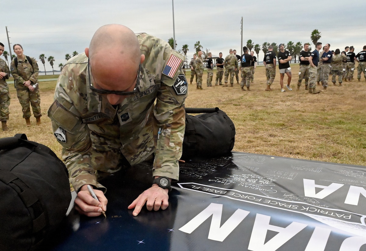 Chief Master Sgt. of the Space Force John Bentivegna signs a banner to commemorate the third annual Guardian Arena at Patrick Space Force Base, Fla., Dec. 9, 2025. Thirty-five teams, comprised of U.S. Space Force Guardians, U.S. Air Force Airmen, civilians, and representatives from international allies and partners, took part in the world’s largest Space Force exercise. The competition emphasizes the importance of cultivating a combat-ready mindset, connecting military and civilian space enterprises, and building esprit de corps by putting the Guardian Ideals into action. (U.S. Air Force photo by Chad Trujillo)