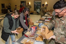 A photo of an Airman and volunteers packaging cookies.