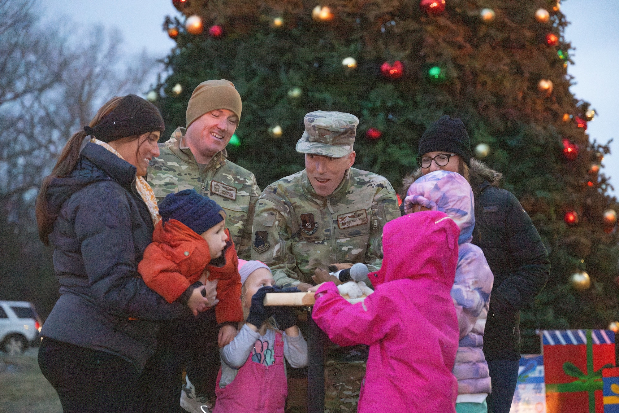 Arnold Engineering Development Complex Commander Col. Grant Mizell, center, and AEDC Senior Enlisted Leader Chief Master Sgt. Evan McCoy receive a helping hand with the plunger used to light the Arnold Air Force Base Christmas tree during the tree lighting ceremony Dec. 4, 2025. The Christmas tree at Arnold AFB, Tenn., headquarters of AEDC, was purchased in 2023 after installation leadership expressed a desire for a Christmas tree to be displayed at a prominent location on the base. The tree measures 40 feet tall and 22 feet wide. It is decorated with approximately 300 ornaments and is topped with a 5-foot 3D five-point star. (U.S. Air Force photo by Keith Thornburgh)