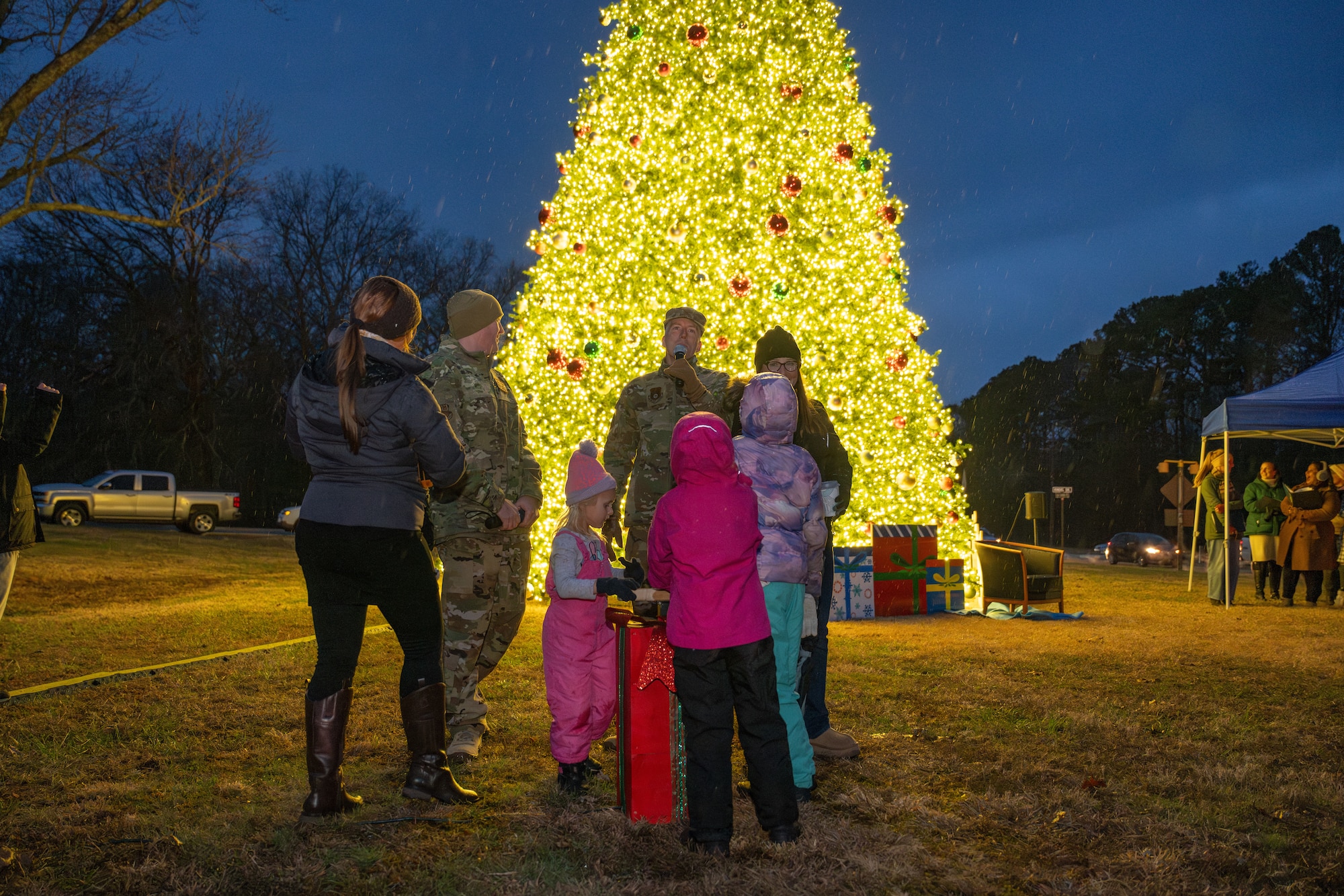 Arnold Engineering Development Complex Commander Col. Grant Mizell, center, speaks to those gathered at the Arnold Air Force Base Christmas tree lighting ceremony Dec. 4, 2025. Pictured to Mizell’s right is AEDC Senior Enlisted Leader Chief Master Sgt. Evan McCoy. The Christmas tree at Arnold AFB, Tenn., headquarters of AEDC, was purchased in 2023 after installation leadership expressed a desire for a Christmas tree to be displayed at a prominent location on the base. The tree measures 40 feet tall and 22 feet wide. It is decorated with approximately 300 ornaments and is topped with a 5-foot 3D five-point star. (U.S. Air Force photo by Keith Thornburgh)