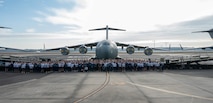 A photo of several people standing in front of a plane.