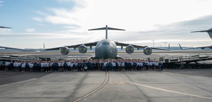 A photo of several people standing in front of a plane.