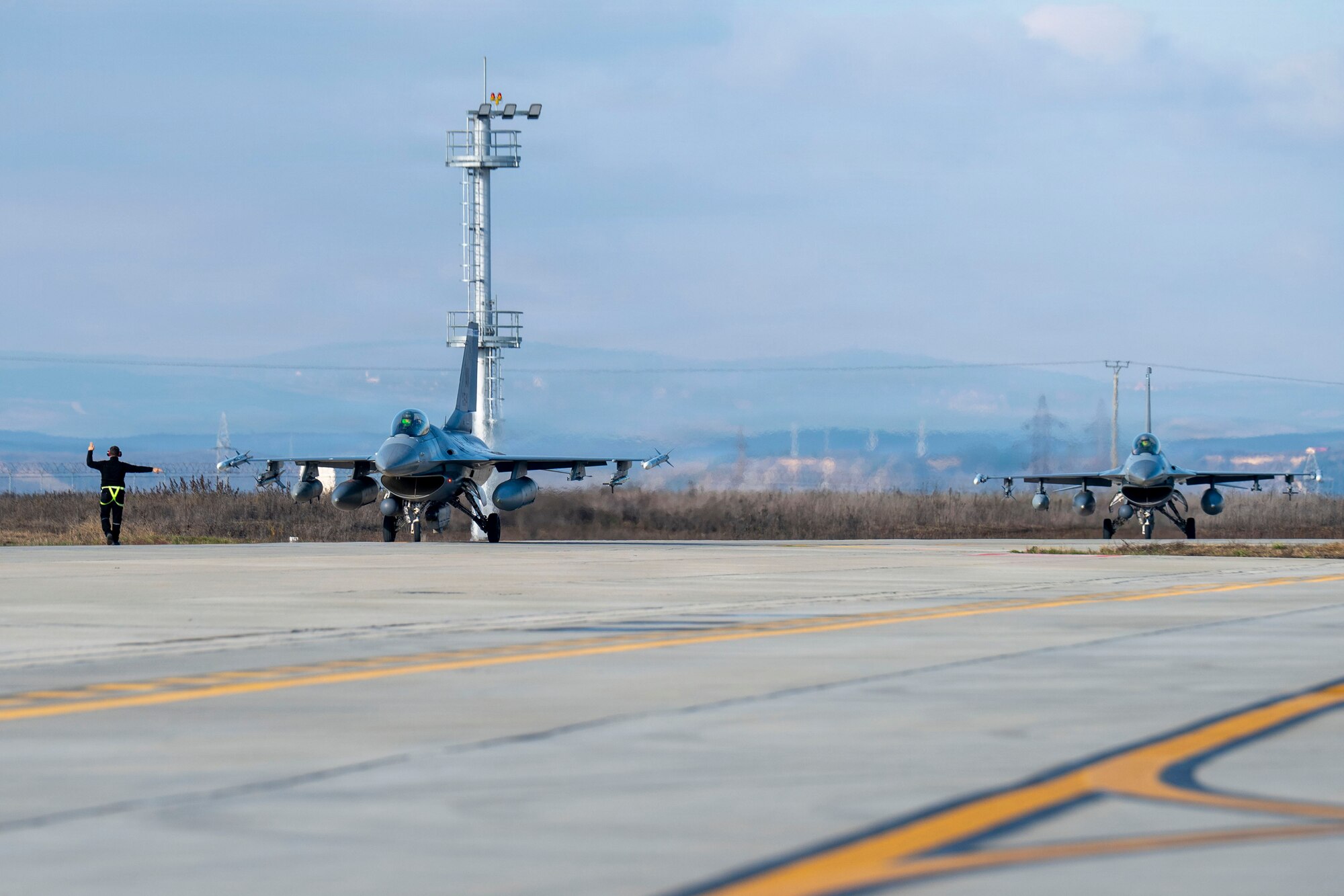 Two U.S. Air Force F-16 Fighting Falcons, assigned to the 510th and 555th Fighter Generation Squadrons at Aviano Air Base, Italy, taxi down the runway during routine Agile Combat Employment operations at Campia Turzii, Romania