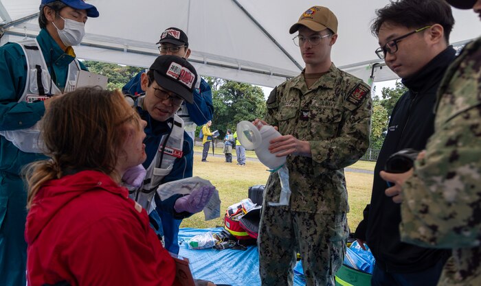 JOGASHIMA PARK, Japan (Nov. 9, 2025) — A U.S. Navy Hospital Corpsman assigned to U.S. Navy Medicine Readiness and Training Command Yokosuka works with Japanese responders to assess and treat a simulated casualty during Big Rescue Kanagawa 2025. The annual exercise is one of Kanagawa Prefecture’s largest disaster-response drills, involving U.S. Naval Hospital Yokosuka, Red Cross Yokosuka and Branch Health Clinic Atsugi personnel working alongside U.S. and Japanese agencies. (U.S. Navy photo by Daniel Taylor/USNMRTC Public Affairs)