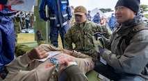 JOGASHIMA PARK, Japan (Nov. 9, 2025) — A U.S. Navy Hospital Corpsman assigned to U.S. Navy Medicine Readiness and Training Command Yokosuka assists Japanese emergency personnel in stabilizing a simulated casualty during Big Rescue Kanagawa 2025. The annual exercise is one of Kanagawa Prefecture’s largest disaster-response drills, involving U.S. Naval Hospital Yokosuka, Red Cross Yokosuka and Branch Health Clinic Atsugi personnel working alongside U.S. and Japanese agencies. (U.S. Navy photo by Daniel Taylor/USNMRTC Public Affairs)