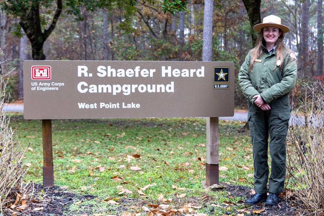 Female Park Ranger standing by a sign.
