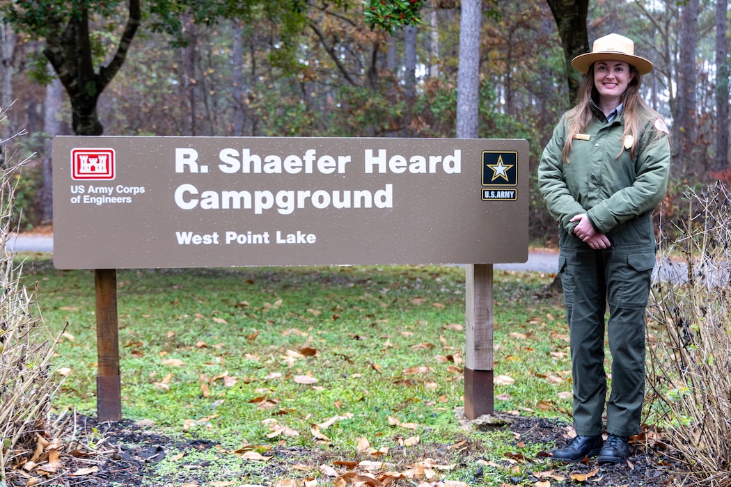 Female Park Ranger standing by a sign.