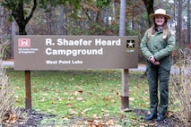 Female Park Ranger standing by a sign.