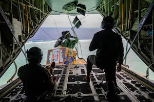 From left, U.S. Air Force Senior Airmen Mark Weinstein and Cody Raymond, 374th Air Expeditionary Wing loadmasters, drop humanitarian bundles.