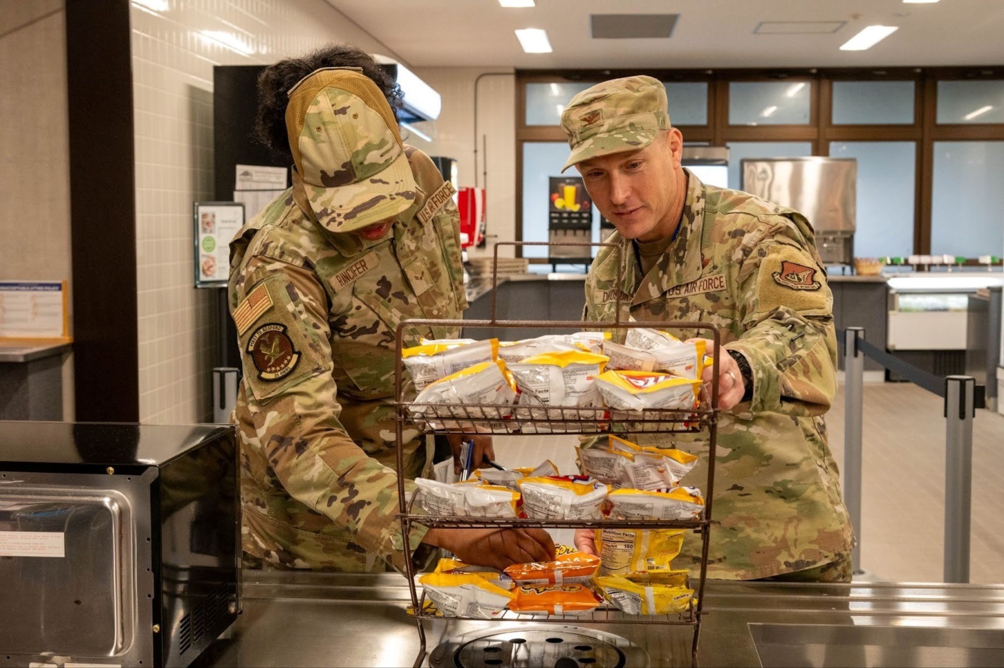 U.S. Air Force Airman 1st Class Tykira Rancifer, 35th Operational Medical Readiness Squadron public health technician, and Col. Paul Davidson, 35th Fighter Wing (FW) commander, inspect a snack display at Misawa Air Base, Japan, Dec. 8,2025. Rancifer’s Wild Weasel of the week nomination demonstrates the dedication and the high standards that keeps the 35th FW operating at its best. (U.S. Air Force photo by Airman 1st Class Jessel Fabara)
