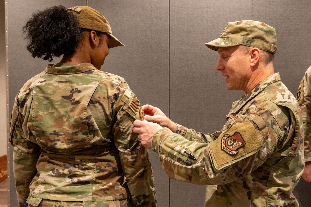 U.S. Air Force Col. Paul Davidson, 35th Fighter Wing (FW) commander, places a 35th FW patch on Wild Weasel of the Week Airman 1st Class Tykira Rancifer, 35th Operational Medical Readiness Squadron public health technician, at Misawa Air Base, Japan, Dec. 8, 2025. Wild Weasel of the Week showcases the commitment that keeps Team Misawa moving day and night. (U.S. Air Force photo by Airman 1st Class Jessel Fabara)