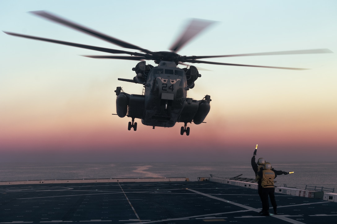 U.S. Navy Aviation Boatswain Mate Handling Airmen Savannah Edwards, left, and Aviation Boatswain’s Mate Handler 3rd Class Darrell Agustin, both assigned to San Antonio-class amphibious transport dock ship USS Portland (LPD 27), guide a CH-53E Super Stallion assigned to Marine Medium Tiltrotor Squadron (VMM) 163 (Reinforced), 11th Marine Expeditionary Unit, during deck landing qualifications in the Pacific Ocean, December 3, 2025. The 11th MEU is currently underway aboard the Boxer Amphibious Ready Group in the U.S. 3rd Fleet area of operations conducting integrated training that enhances lethality and warfighting readiness. (U.S. Marine Corps photo by Cpl. Avery Wayland)