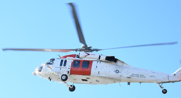 An MH-60S Seahawk helicopter from the Naval Air Station (NAS) Patuxent River "SAR Dogs" unit scans the coastline during a challenging L00A qualification flight. The aircrew was tasked with locating a simulated crash site with no prior location data. This unscripted scenario is a critical component of the qualification process, ensuring the SAR team can effectively respond to distress calls when precise location data is unavailable.