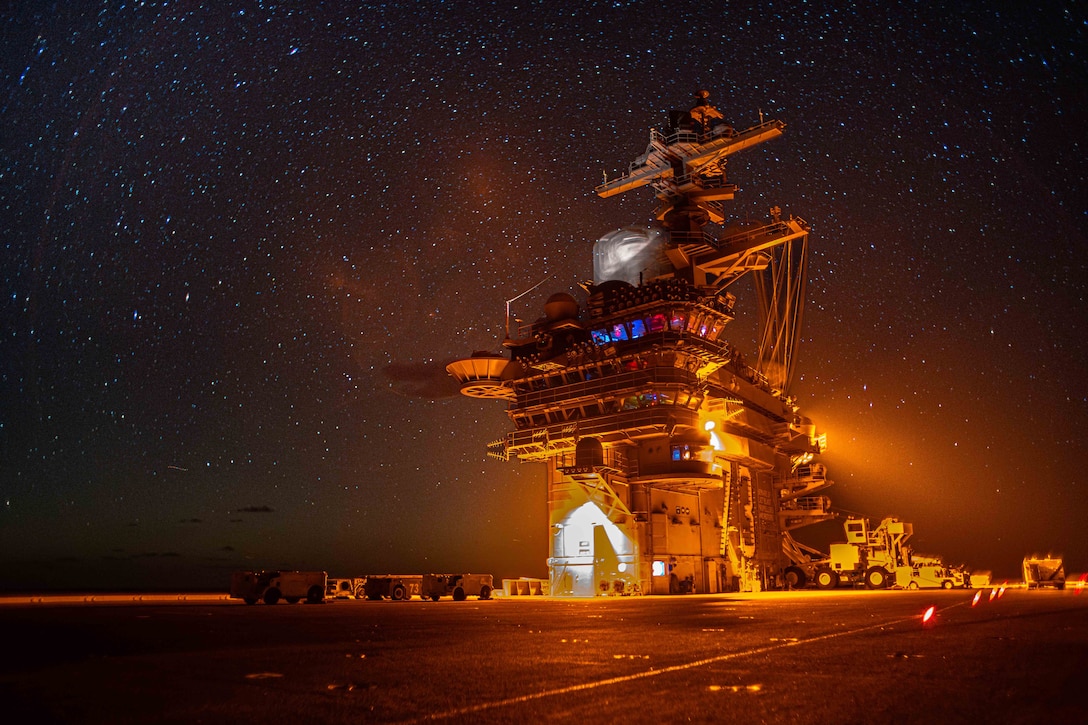 A ship illuminated by white and blue lights sails under a starry sky.