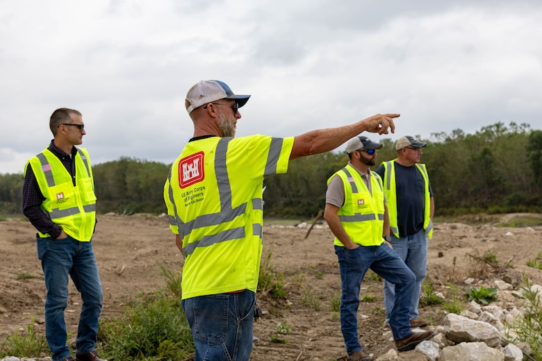 Kansas City District employee pointing towards repaired river control structure from land.