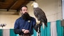 A representative from the World Bird Sanctuary holds a bald eagle on a tall stick during an educational program for students attending the Quad City Bald Eagle Days event.