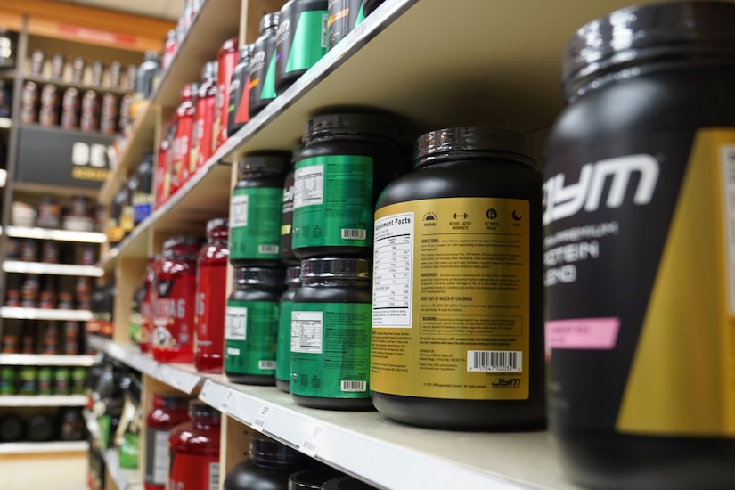 Plastic bottles containing various nutritional supplements are lined up for sale on store shelves.